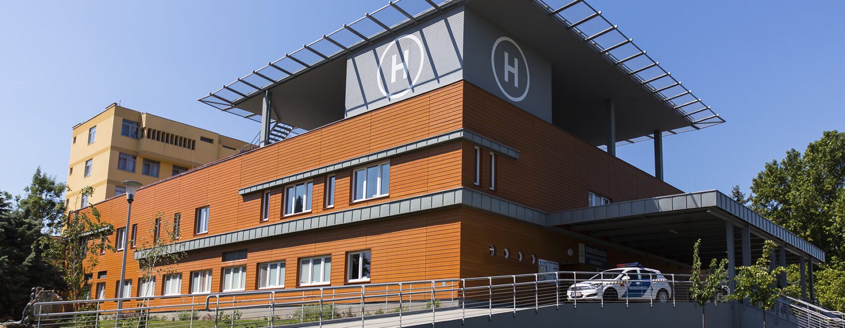 Modern kórház épülete, helikopter leszállóhellyel.